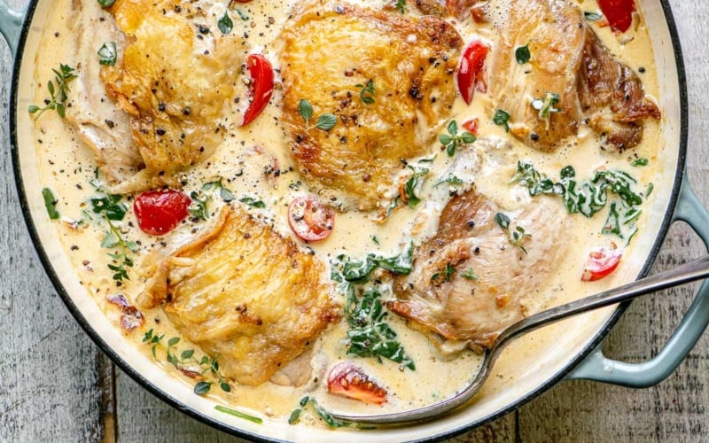 Tuscan Chicken simmering in a pot with serving spoon.