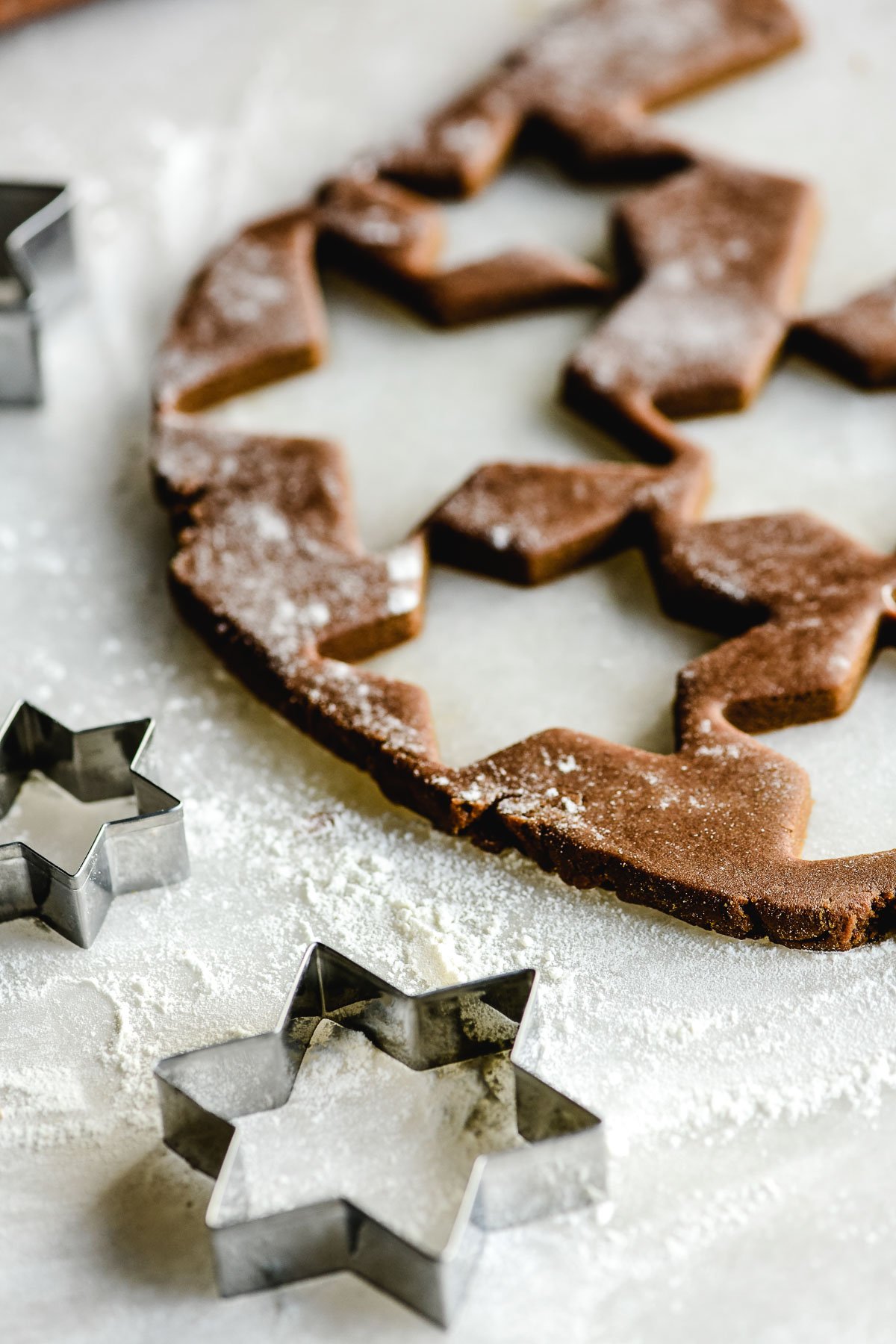 Baked star-shaped gingerbread cookies powdered with sugar for Christmas on  baking parchment paper near pine cones and twigs, dried orange slices and  cinnamon sticks. Flat lay 27025793 Stock Photo at Vecteezy