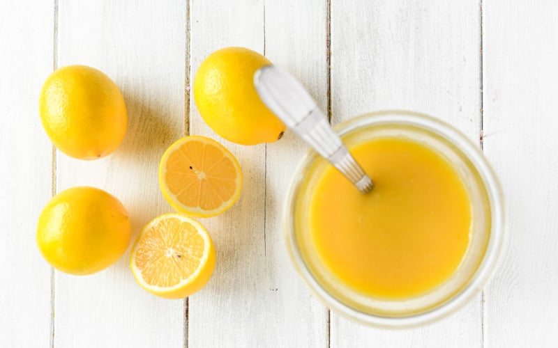 honey Meyer lemon curd in a jar with spoon and lemons