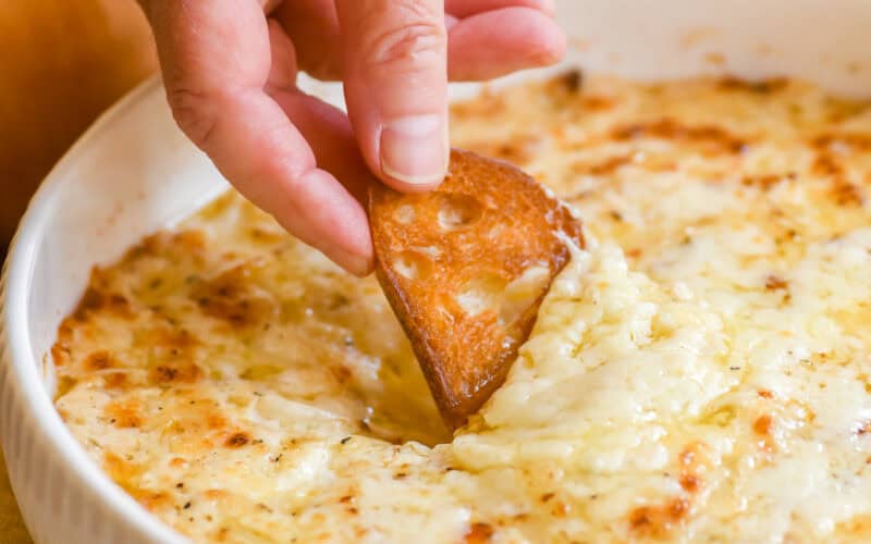 Dipping toasted bread into a baked Vidalia onion dip.