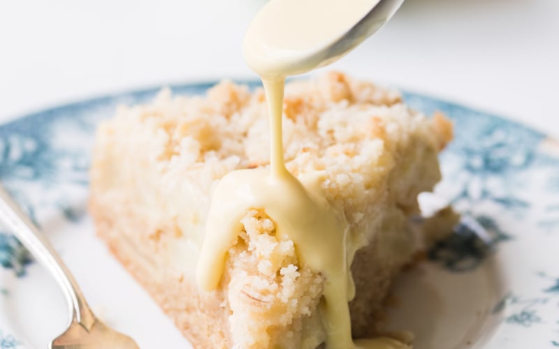 spooning custard sauce on an Irish Apple Cake