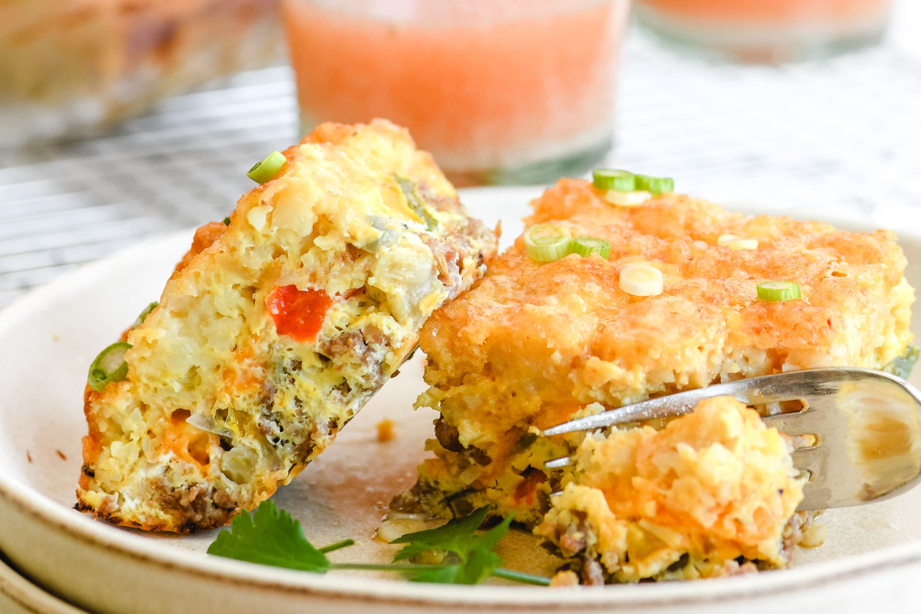 Breakfast casserole with Tater Tot crust, on a plate with fork and juice