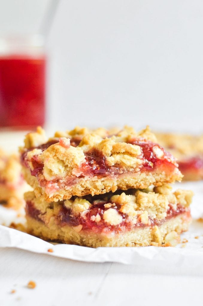 A stack of strawberry jam crumble bars on parchment paper.