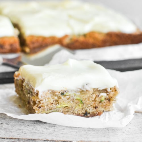 A slice of zucchini sheet cake on a piece of parchment paper.