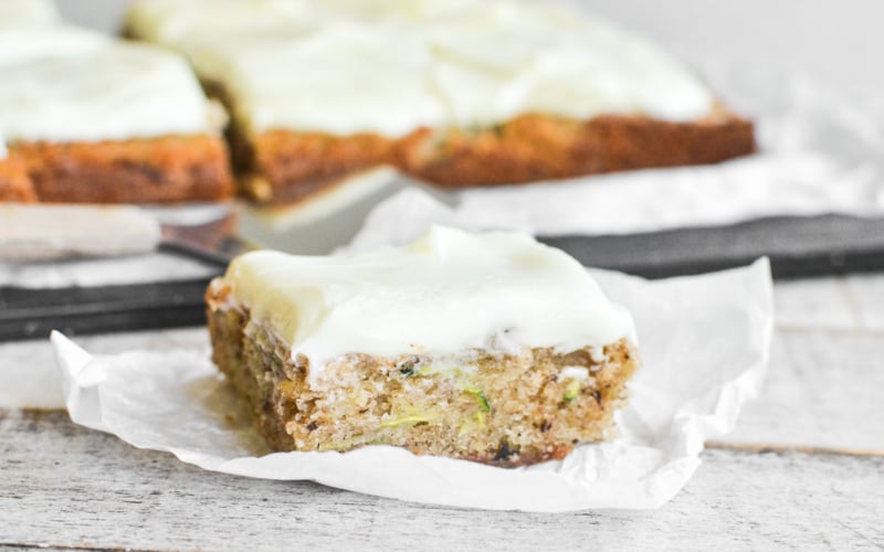 A slice of zucchini sheet cake on a piece of parchment paper.