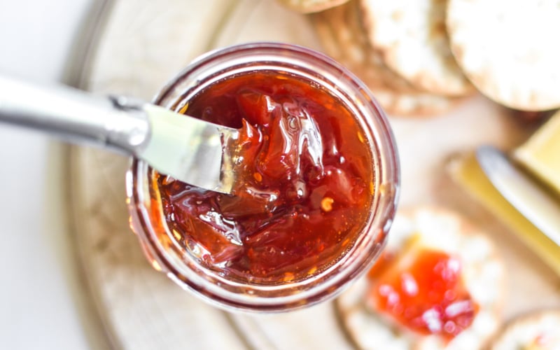 A jar of tomato jam with a small knife.