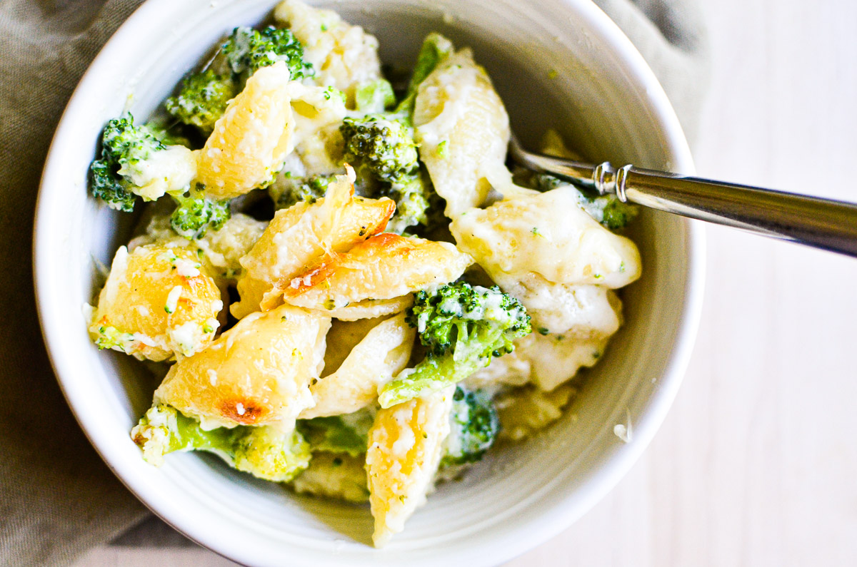 Overhead of a bowl of broccoli and white cheddar baked shells with a fork.