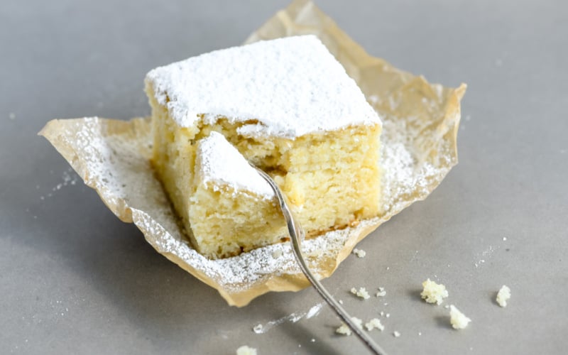 taking a bite of a powdered sugar doughnut cake
