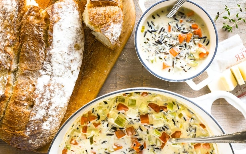 a pot of wild rice soup with bread