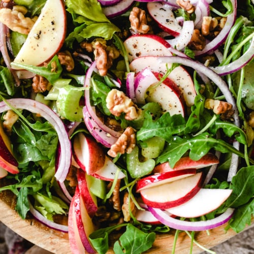 apple celery and walnut salad in a wooden bowl with salad servers