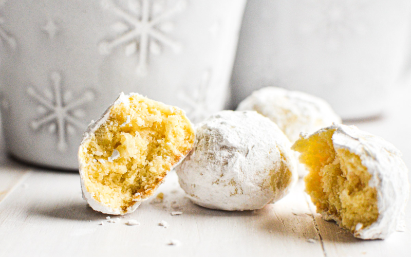 Coconut snowball cookies on a white wooden surface.