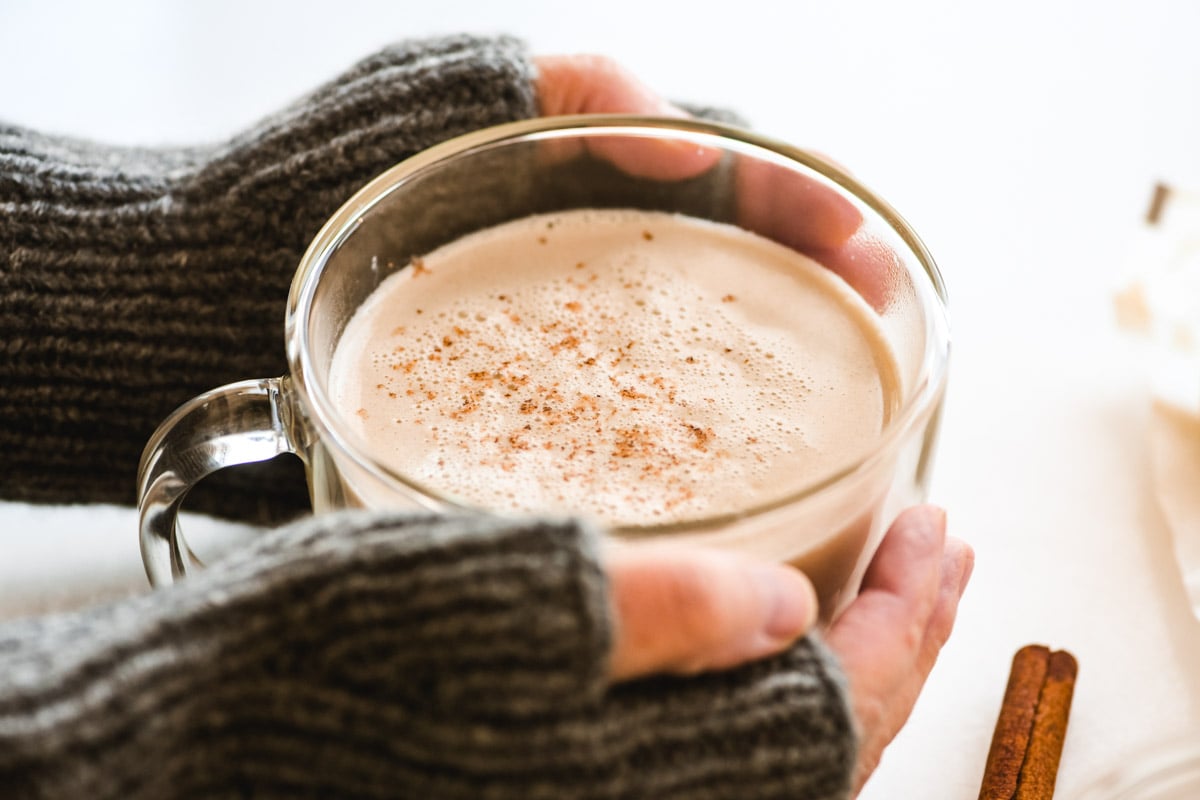holding a butterscotch steamer in a glass mug.
