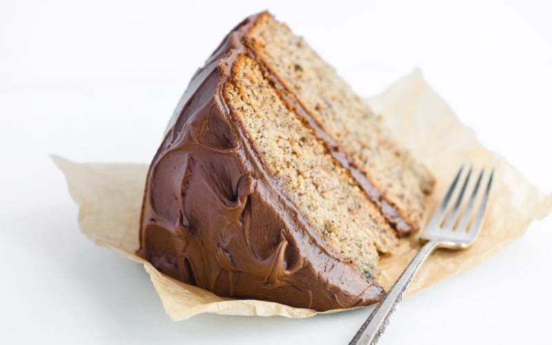 A slice of banana cake with Nutella frosting on parchment paper