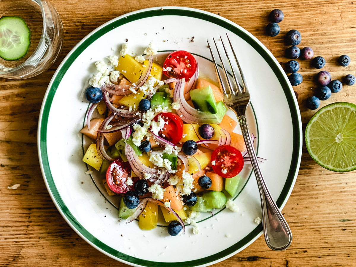 cantaloupe and mango salad in a bowl with fork