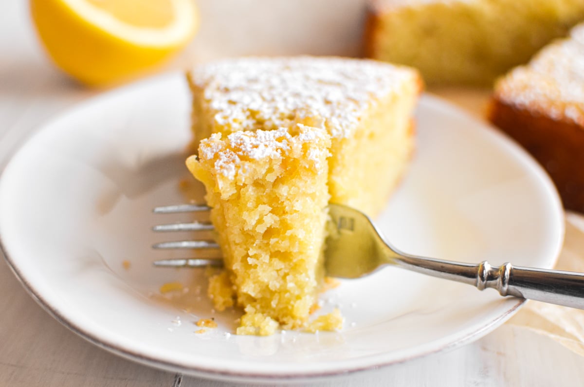 taking a bite of a slice of lemon olive oil cake.
