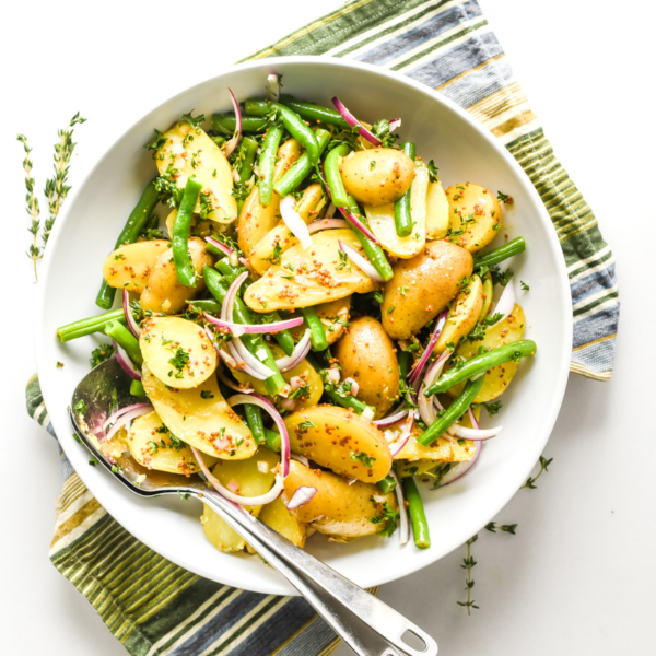 French Potato Salad in a white bowl on a striped napkin