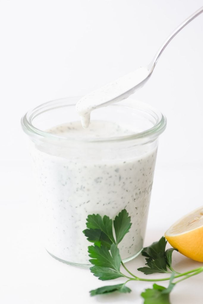 dipping a spoon into a jar of homemade ranch dressing