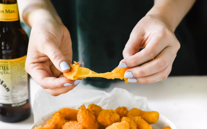 Pulling apart a gooey cornflake crusted cheese curd