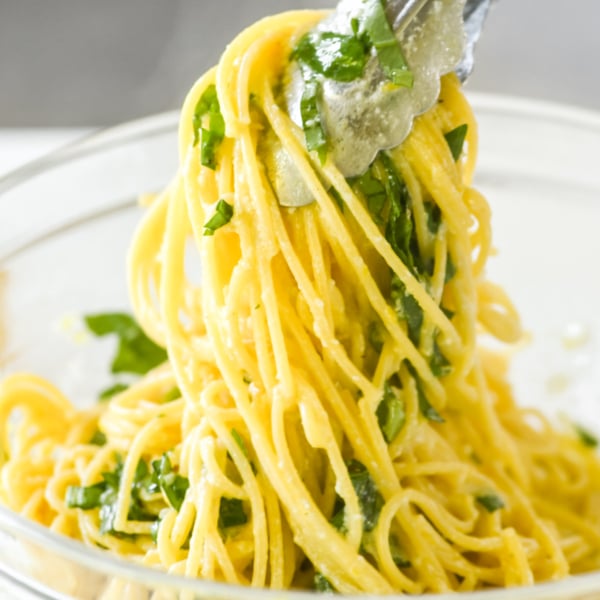 tossing lemon spaghetti with tongs