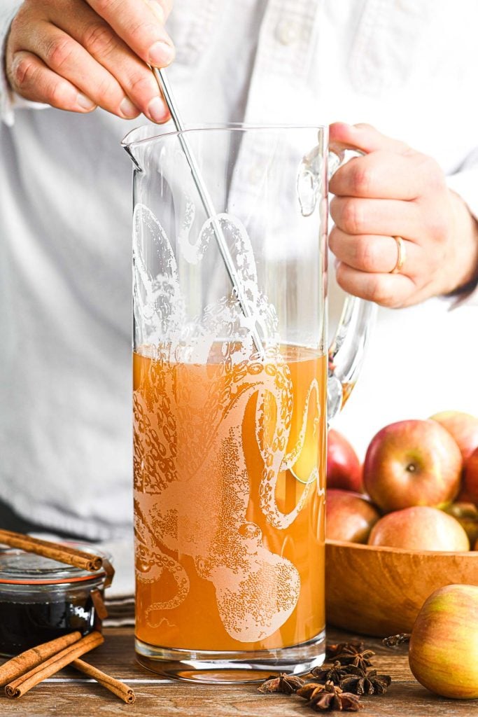 Stirring mezcal apple cider cocktail in a pitcher