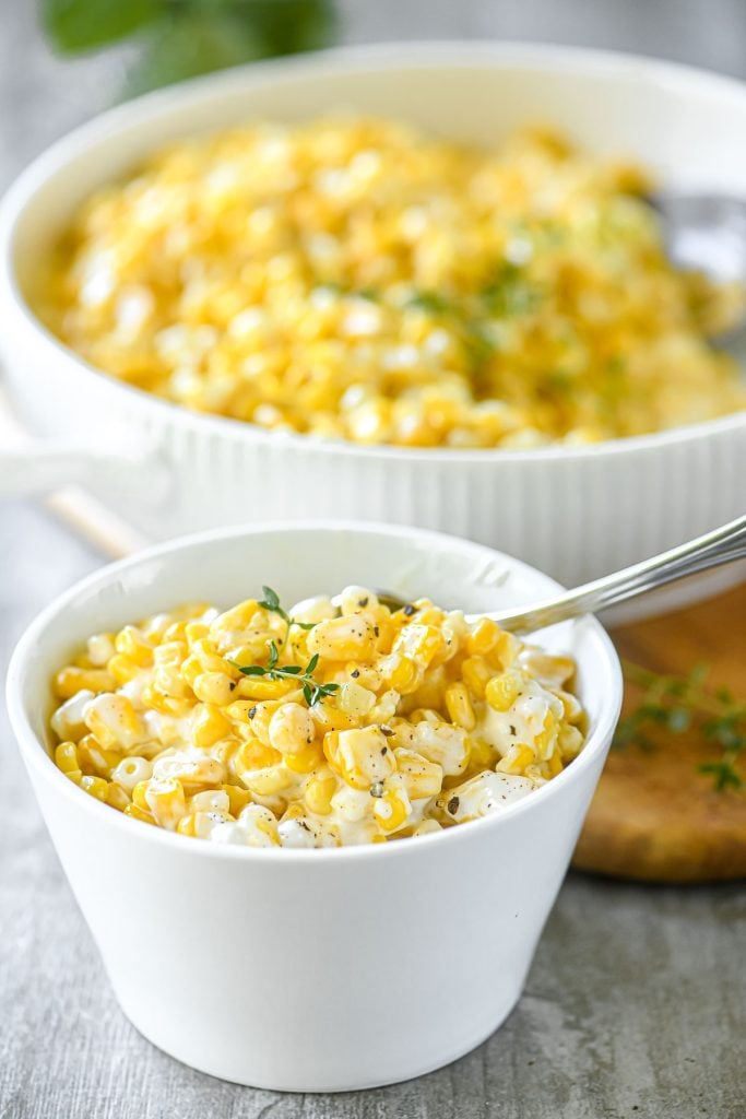 creamed corn in a bowl with thyme sprig