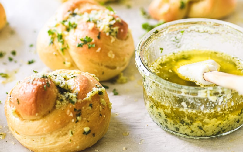garlic knots, being brushed with garlic butter.