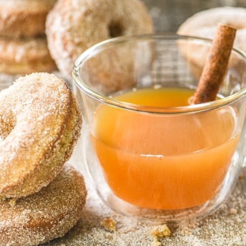apple cider doughnuts with cider in a mug with cinnamon stick