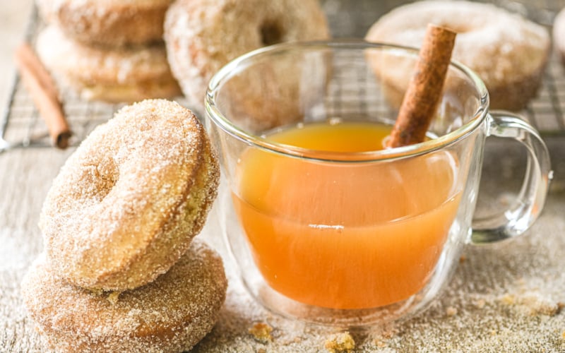 apple cider doughnuts with cider in a mug with cinnamon stick