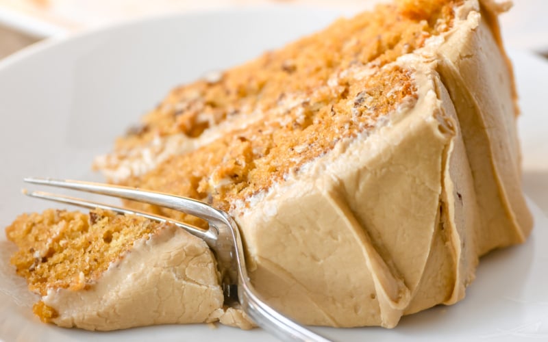A slice of pumpkin layer cake with caramel frosting.