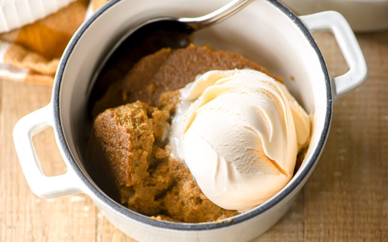 A bowl of Indian Pudding with a scoop of vanilla ice cream on top.