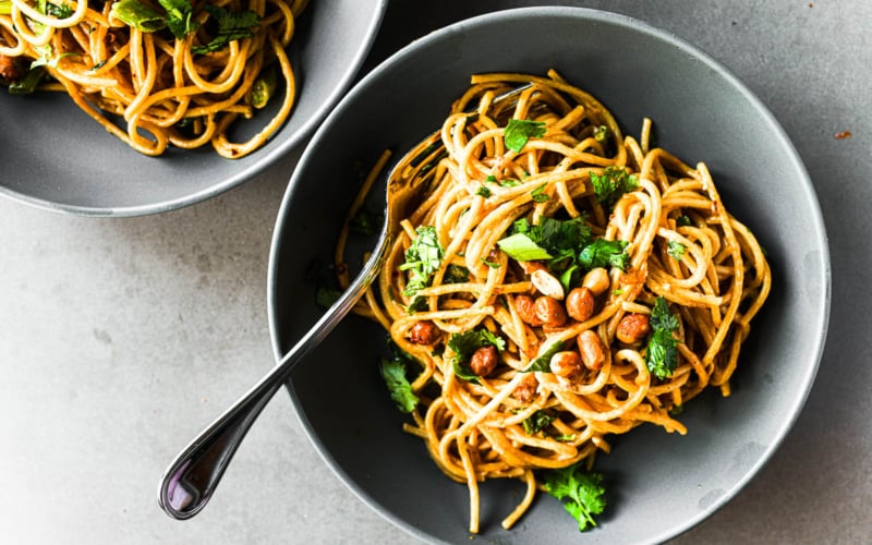 A bowl of peanut butter noodles with a fork.