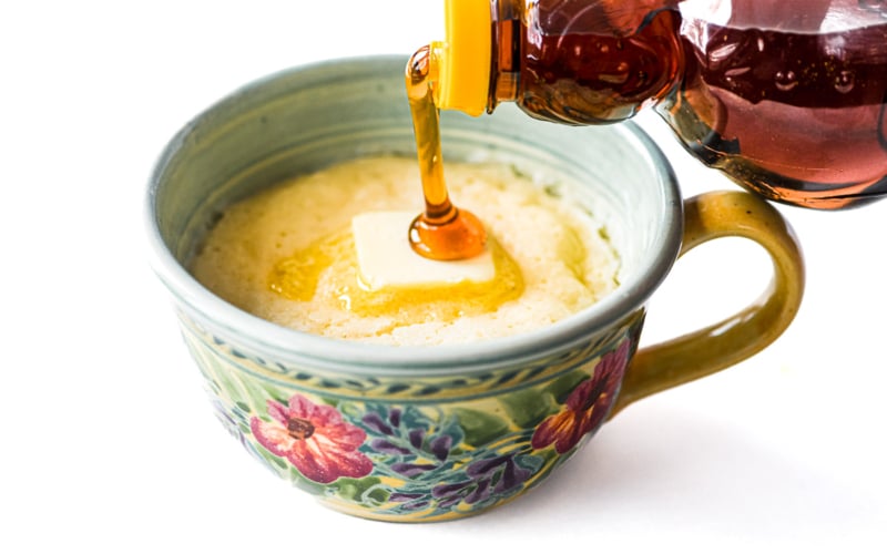 Drizzling syrup onto a pancake in a mug.