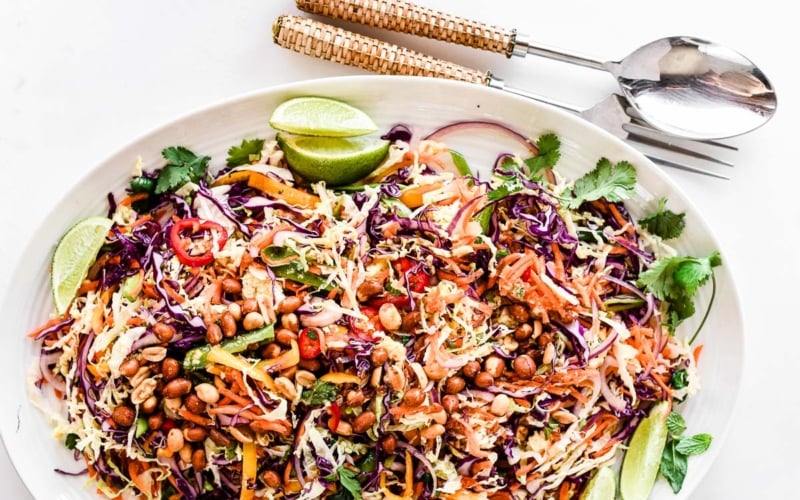 Thai Salad on a platter with serving utensils.