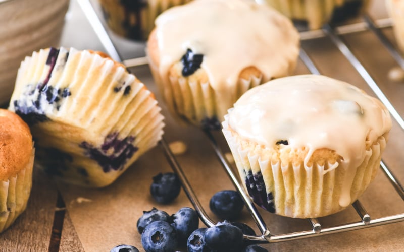 blueberry pancake muffins on a rack, with blueberries.