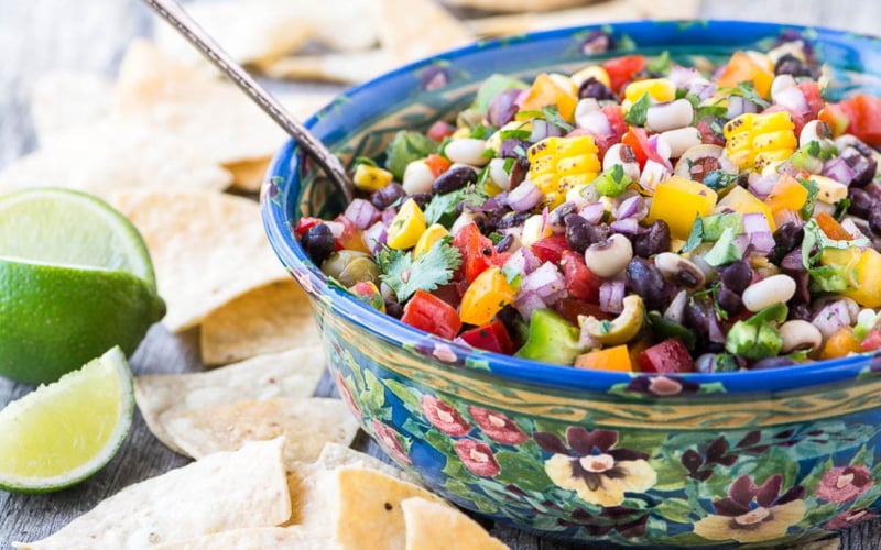 cowboy caviar salsa with chips and lime wedges.