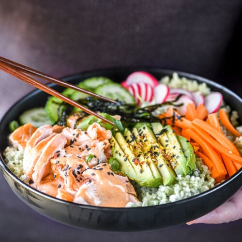 man holding a bowl of salmon sushi rice.