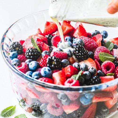 pouring dressing on a berry salad.