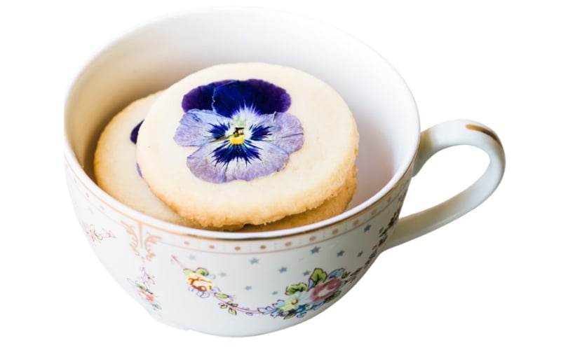 tea cup with pansy cookies.