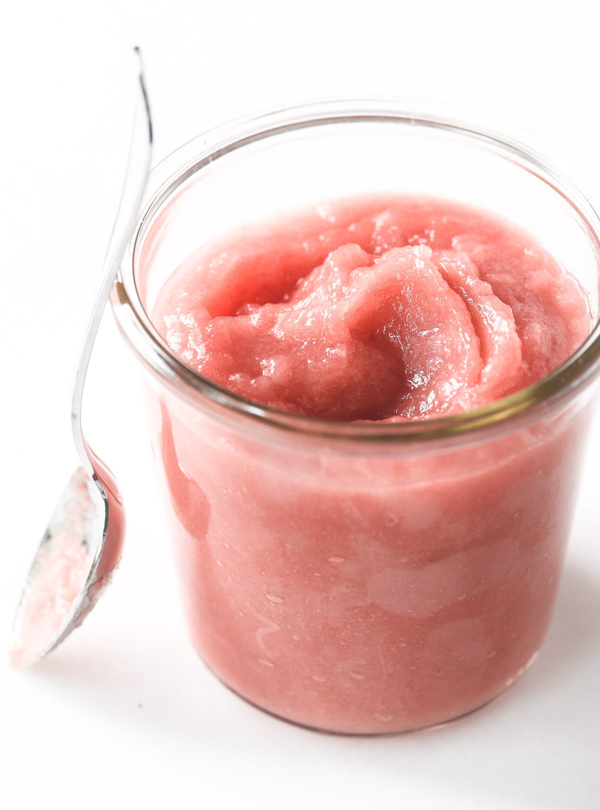 A jar of rhubarb applesauce with spoon.