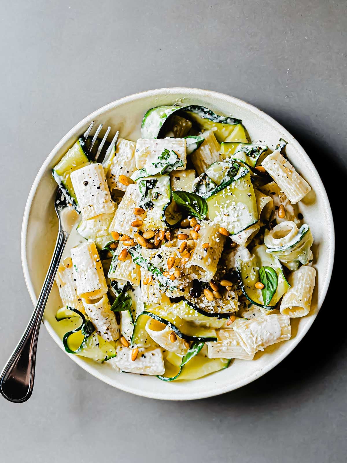 Creamy lemon pasta with zucchini in a shallow bowl with fork.
