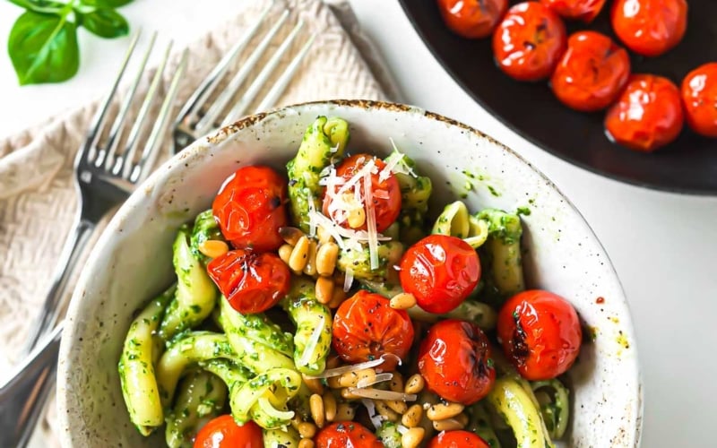 pesto pasta with blistered tomatoes, and fresh basil.