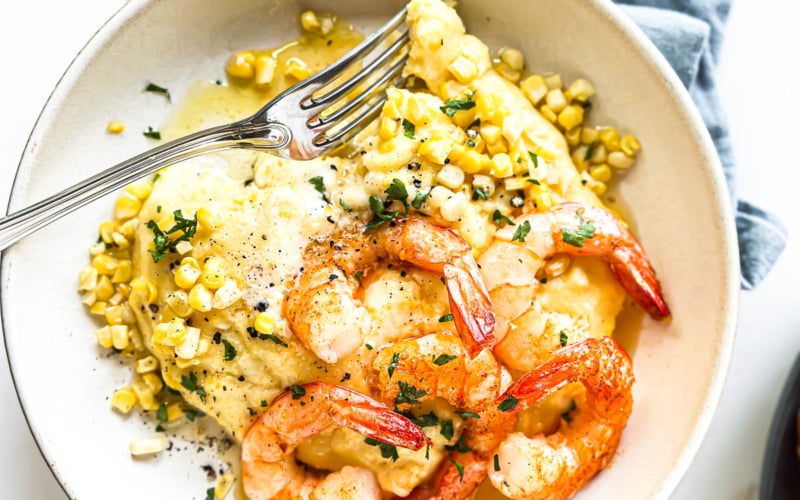 sweet corn polenta with shrimp on a plate with fork.
