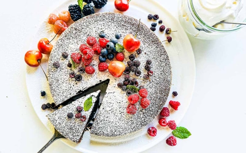 Gluten free Chocolate Olive Oil Cake, topped with powdered sugar and fruit.