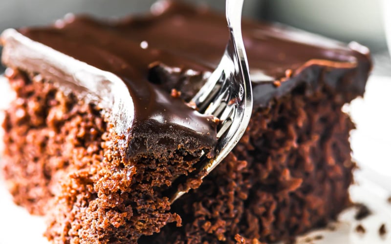 Taking a bite of a chocolate sheet cake with a fork.