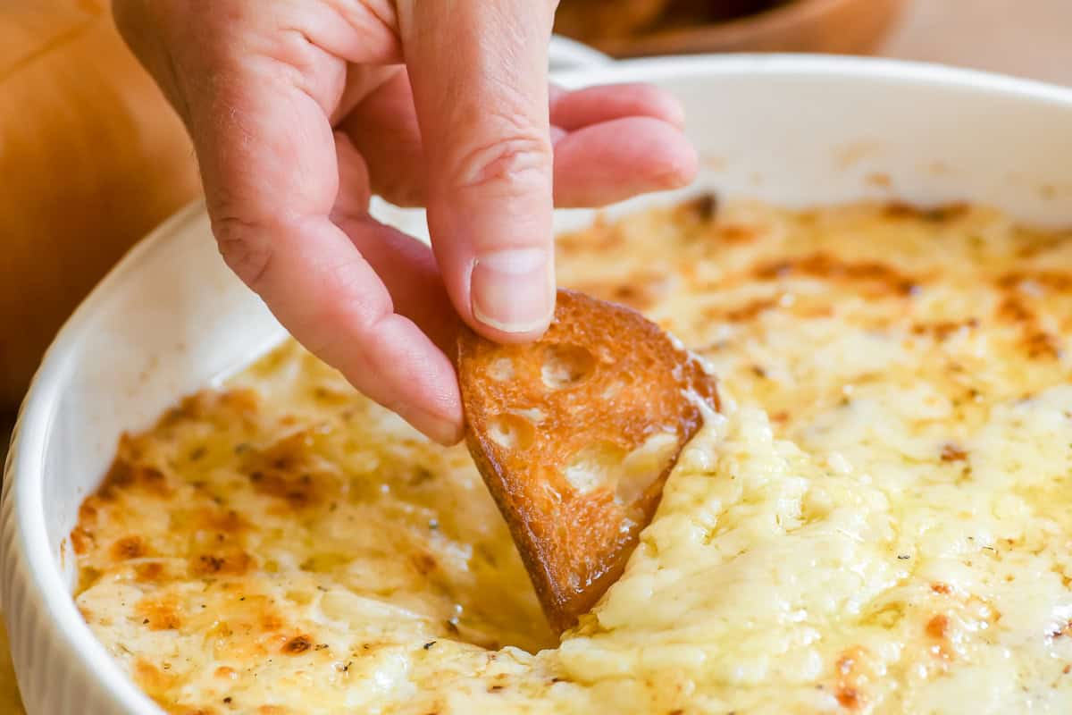 Scooping hot cheesy Vidalia onion dip with toasted bread.