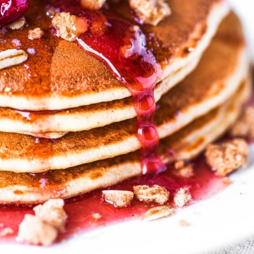 Cranberry crumble pancakes with cranberry maple syrup dripping down.