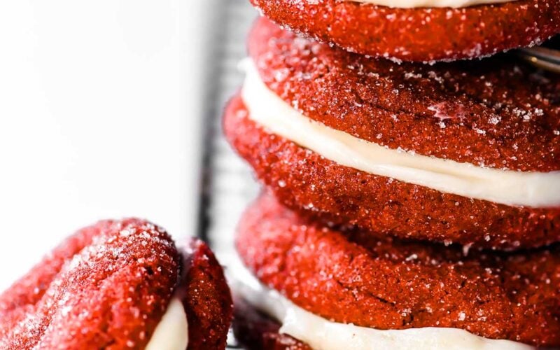 A stack of red velvet cookies, filled with cream cheese frosting.