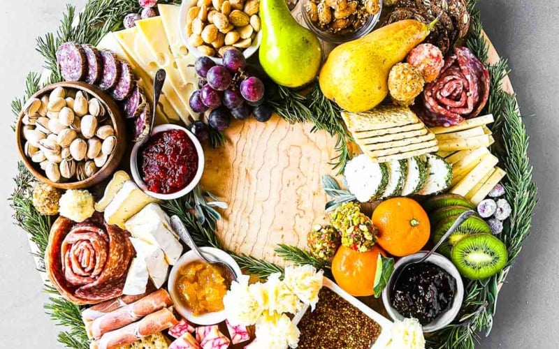 Appetizer wreath with fruits, nuts, cheese, and crackers.