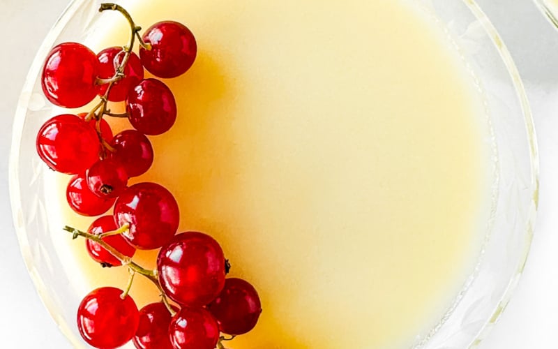 Lemon cream in a glass topped with red currants.