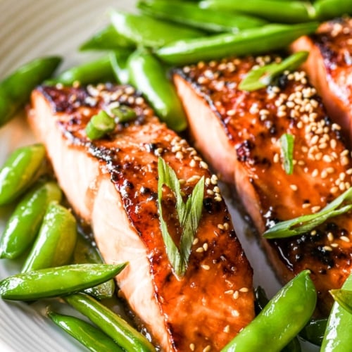 Miso glazed salmon on a plate with pea pods.